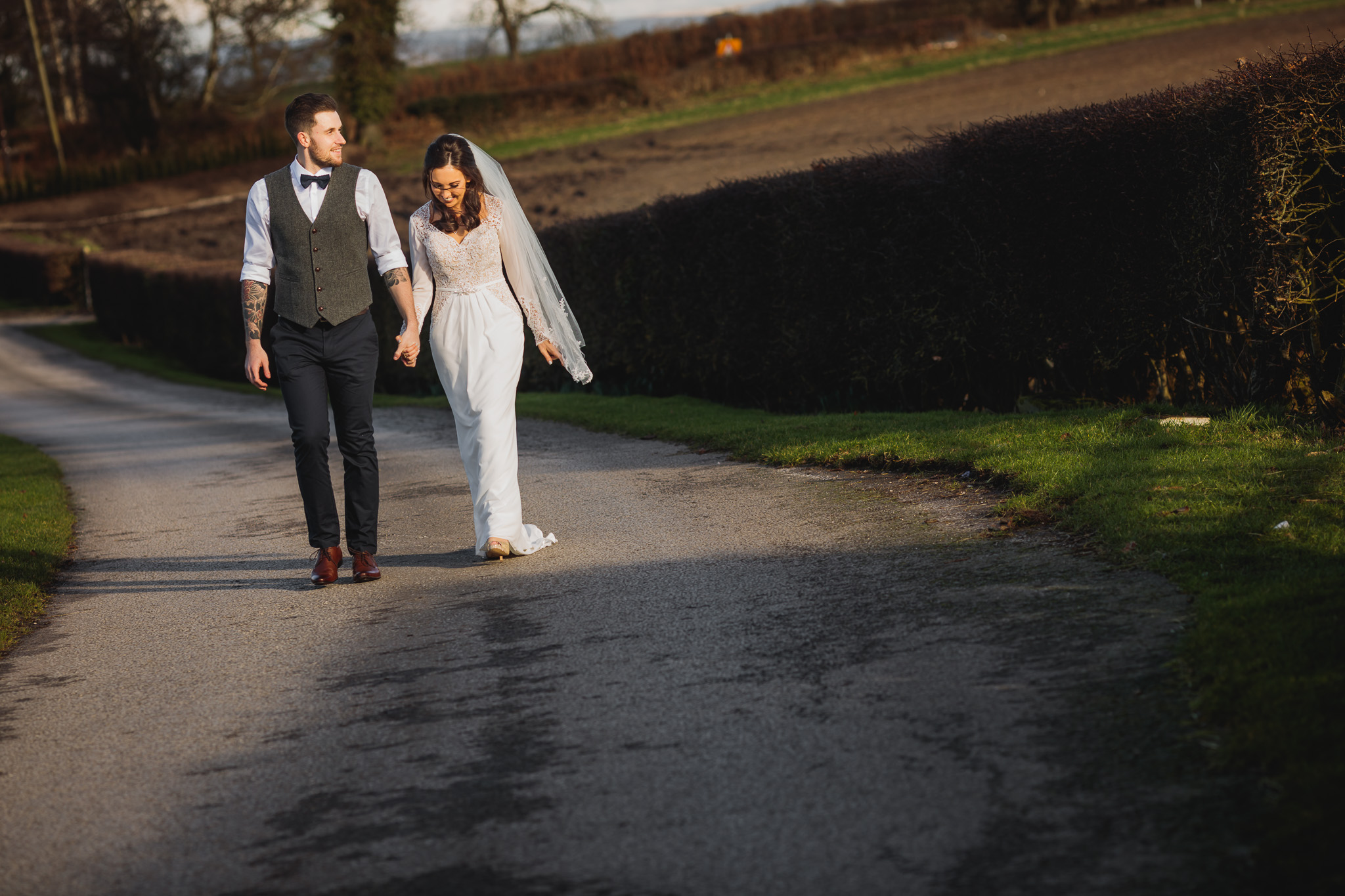A wedding couple walk up the drive at Sandhole Oak Barn, Cheshire.